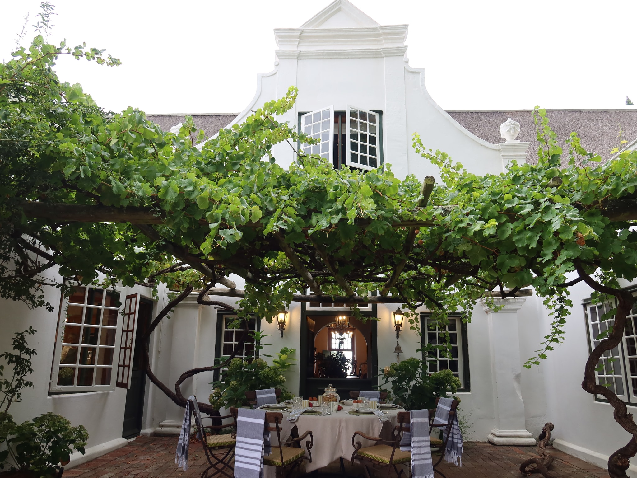 Navarre Residence courtyard with grapevine pergola and Cape Dutch gable