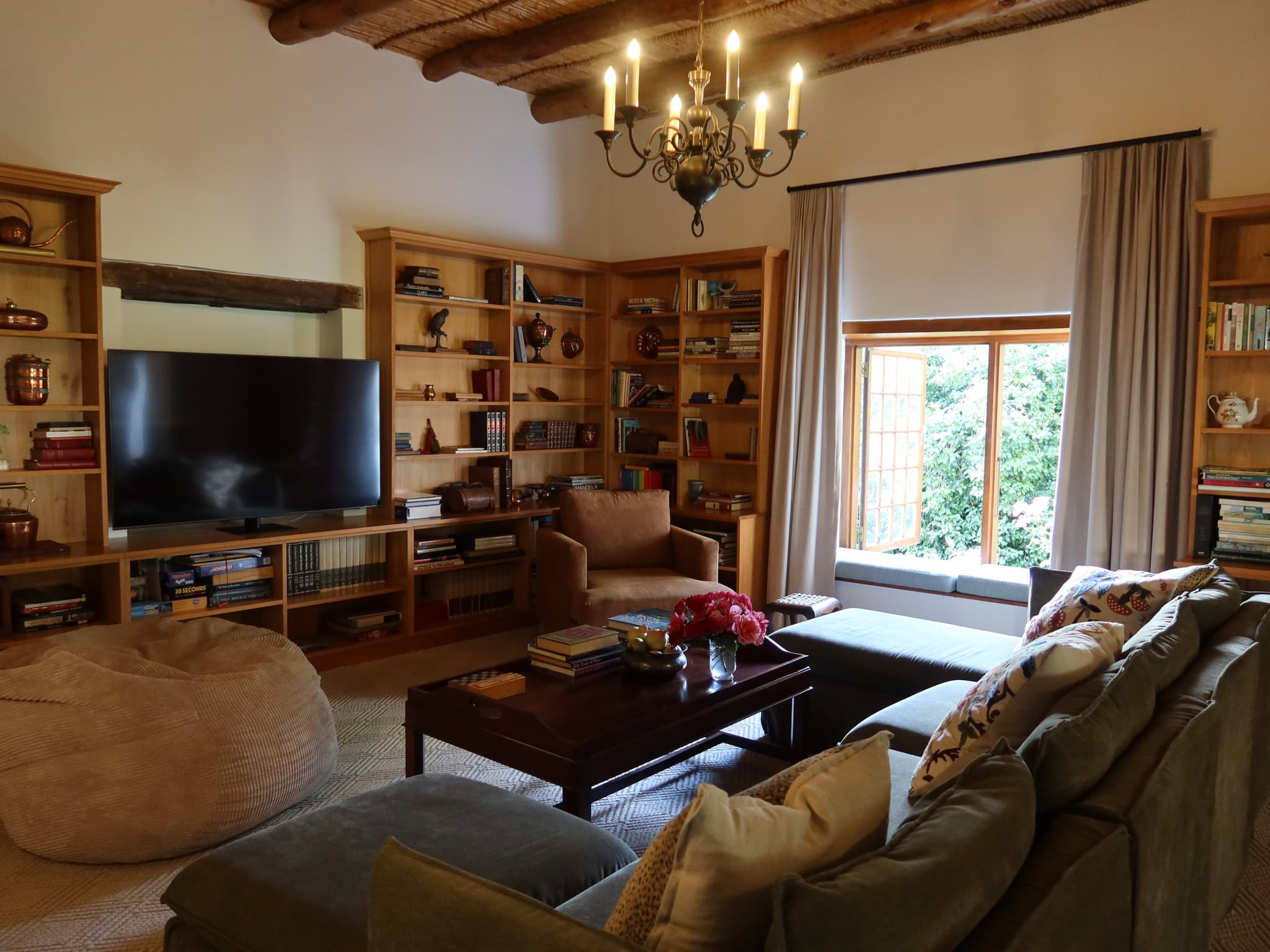 TV room with bookshelves, bean bag, sofa, and wooden beam ceiling