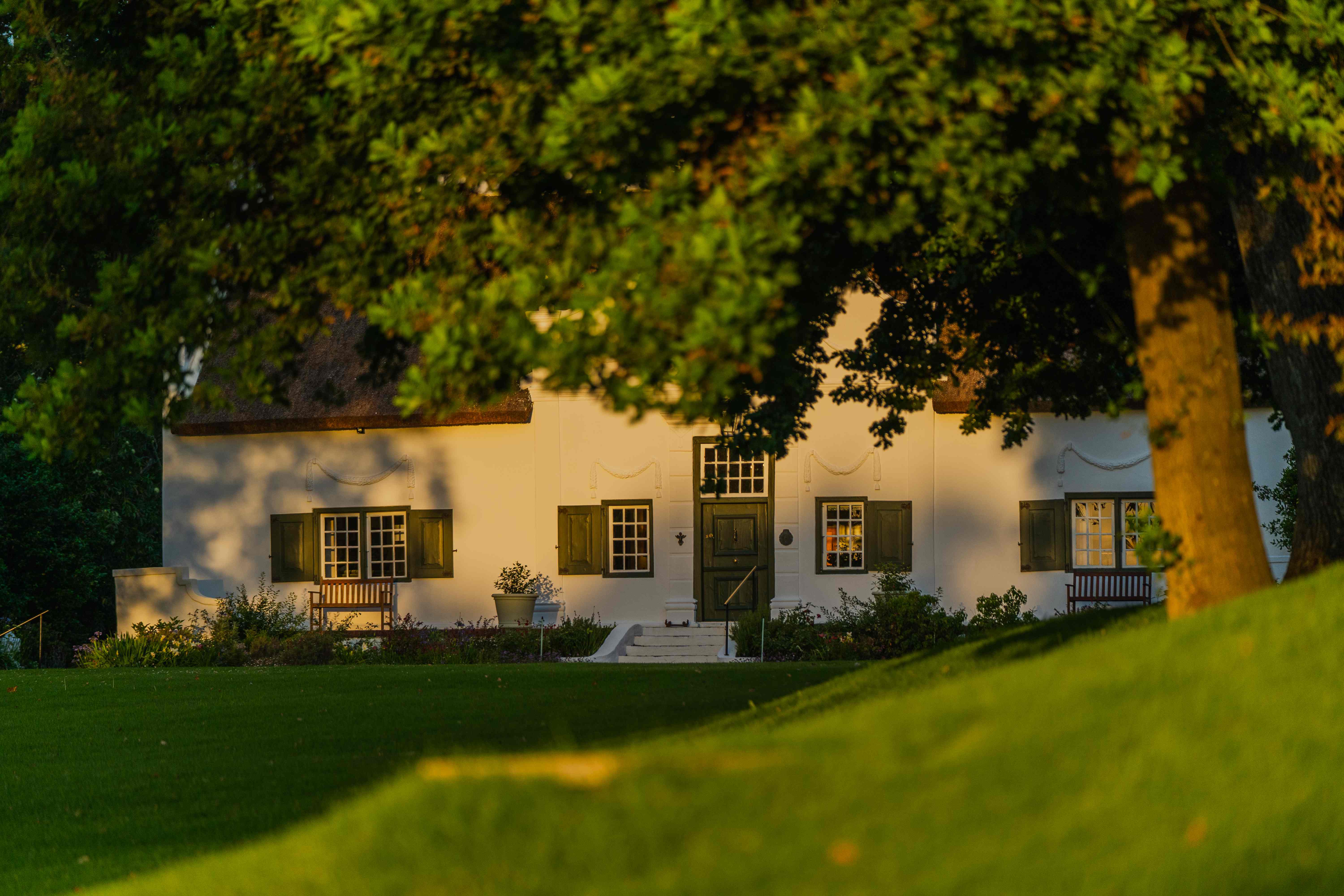 Navarre manor house at golden hour with green shutters and oak trees