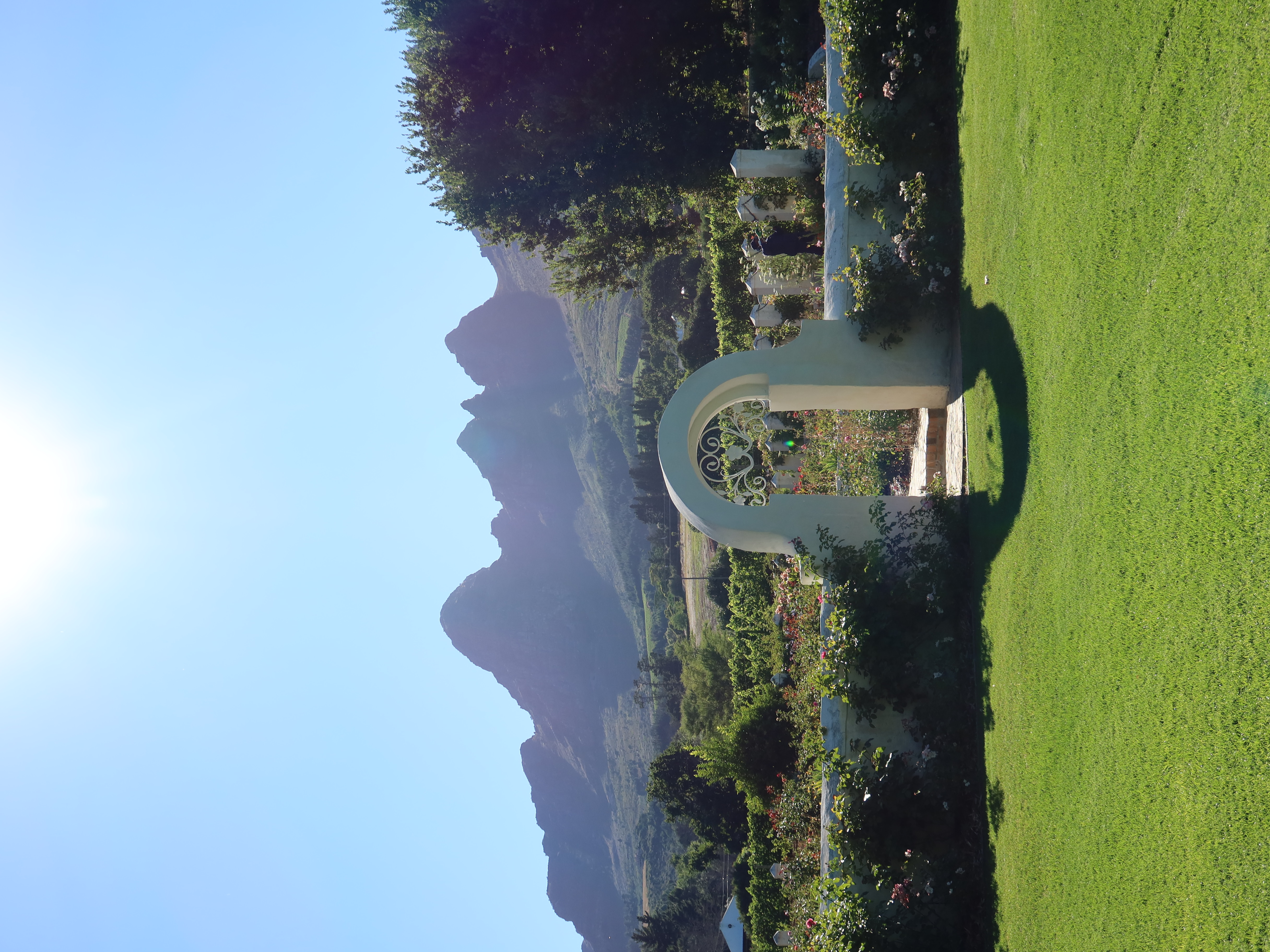 White garden archway with Helderberg mountains and rose garden